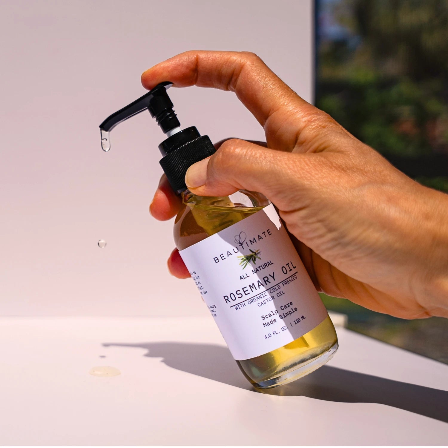 hand holding rosemary oil that is dripping from the bottle