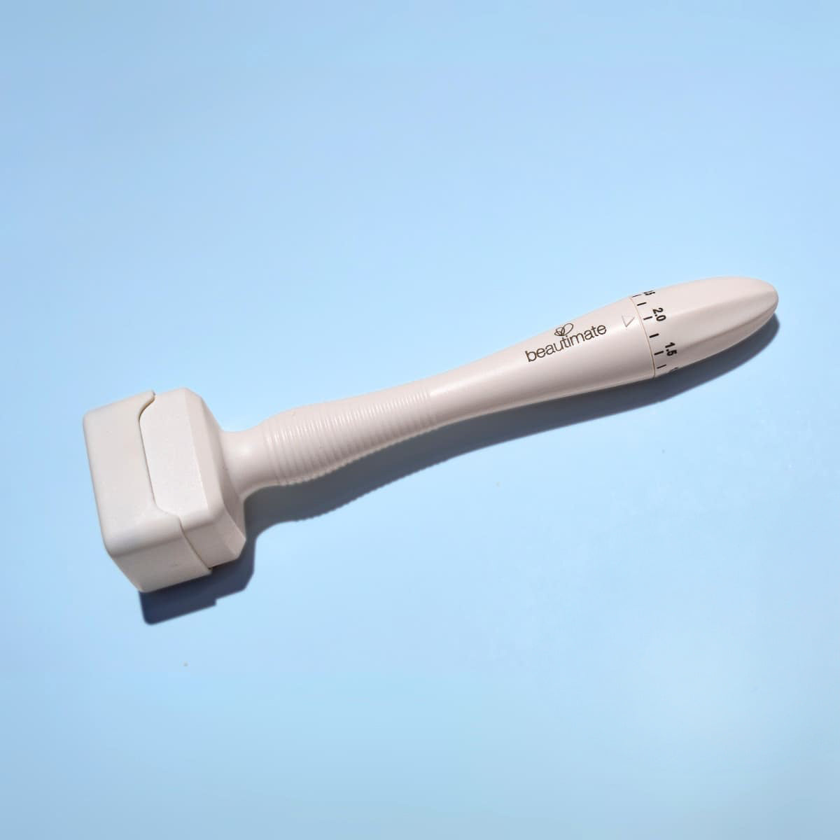 White skin care tool adjustable derma stamp with brand name beautimate on a light blue background