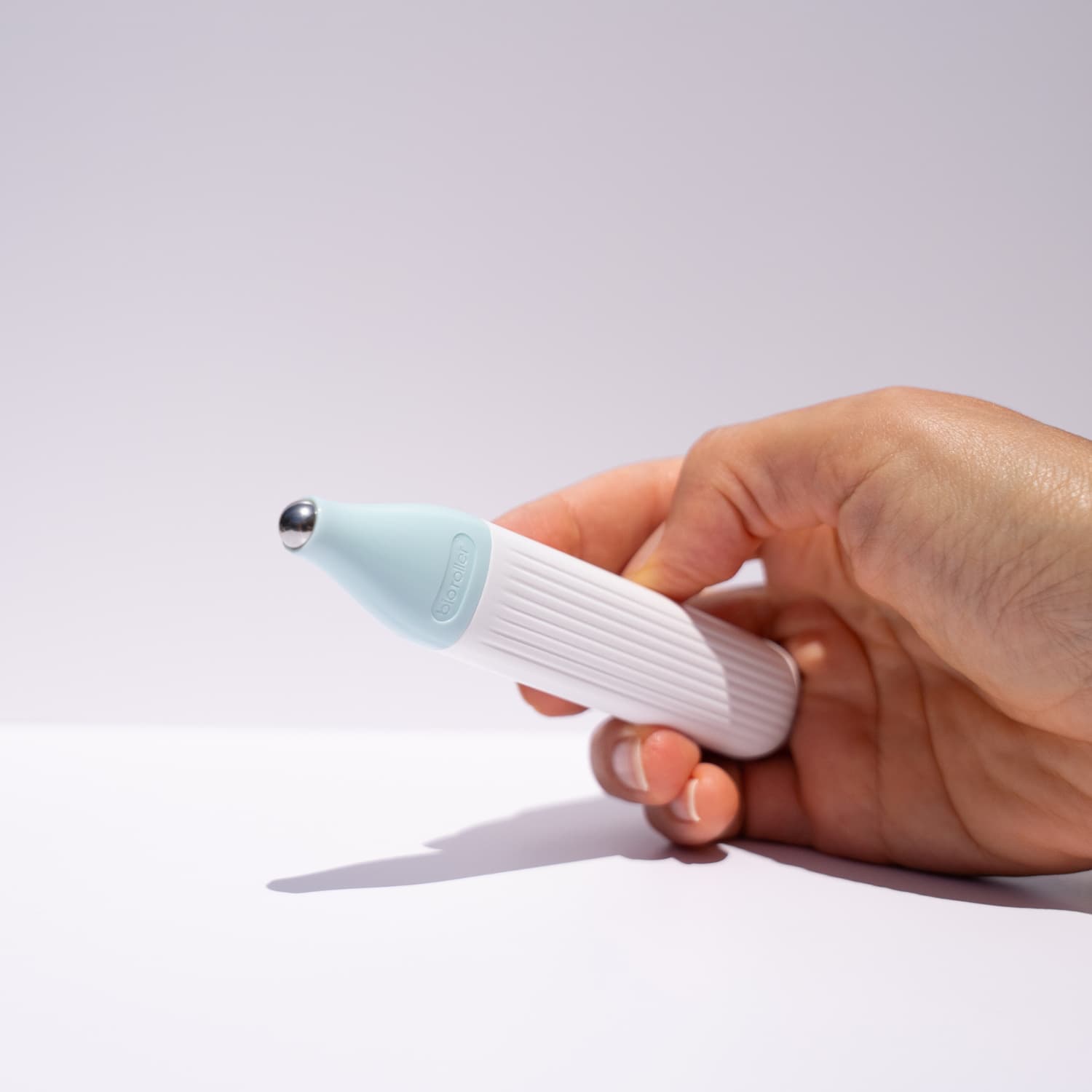 hand holding under eye massaging roller to de-puff the skin