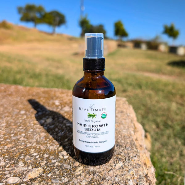 Hair growth serum bottle labeled 'BEAUTIMATE' on a stone surface with a grassy field background.